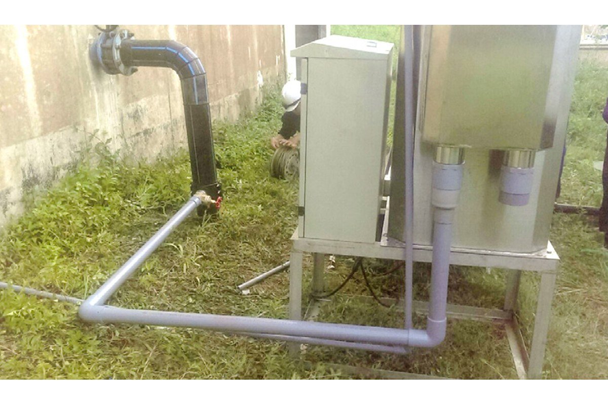 Đường ống nhựa đấu nối vào cụm bồn inox, với van trên tuyến ống cạnh chân thiết bị.